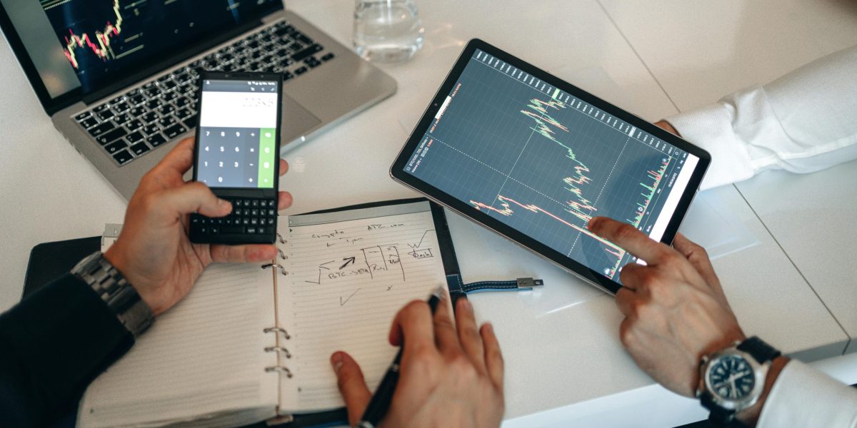 Business professionals analyzing charts on digital devices during a meeting.
